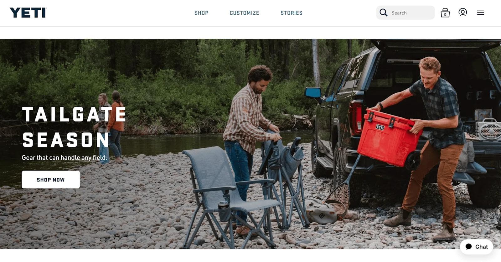 yeti web design Men preparing for tailgating by a river, with camping chairs and a YETI cooler in a scenic outdoor setting.