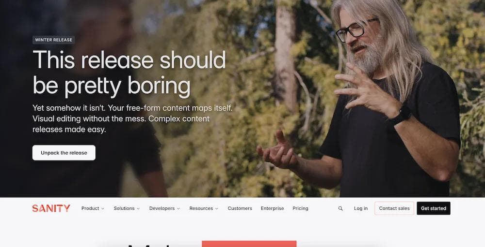 sanity A man with long hair and glasses gestures while discussing a winter software release on a website for Sanity.